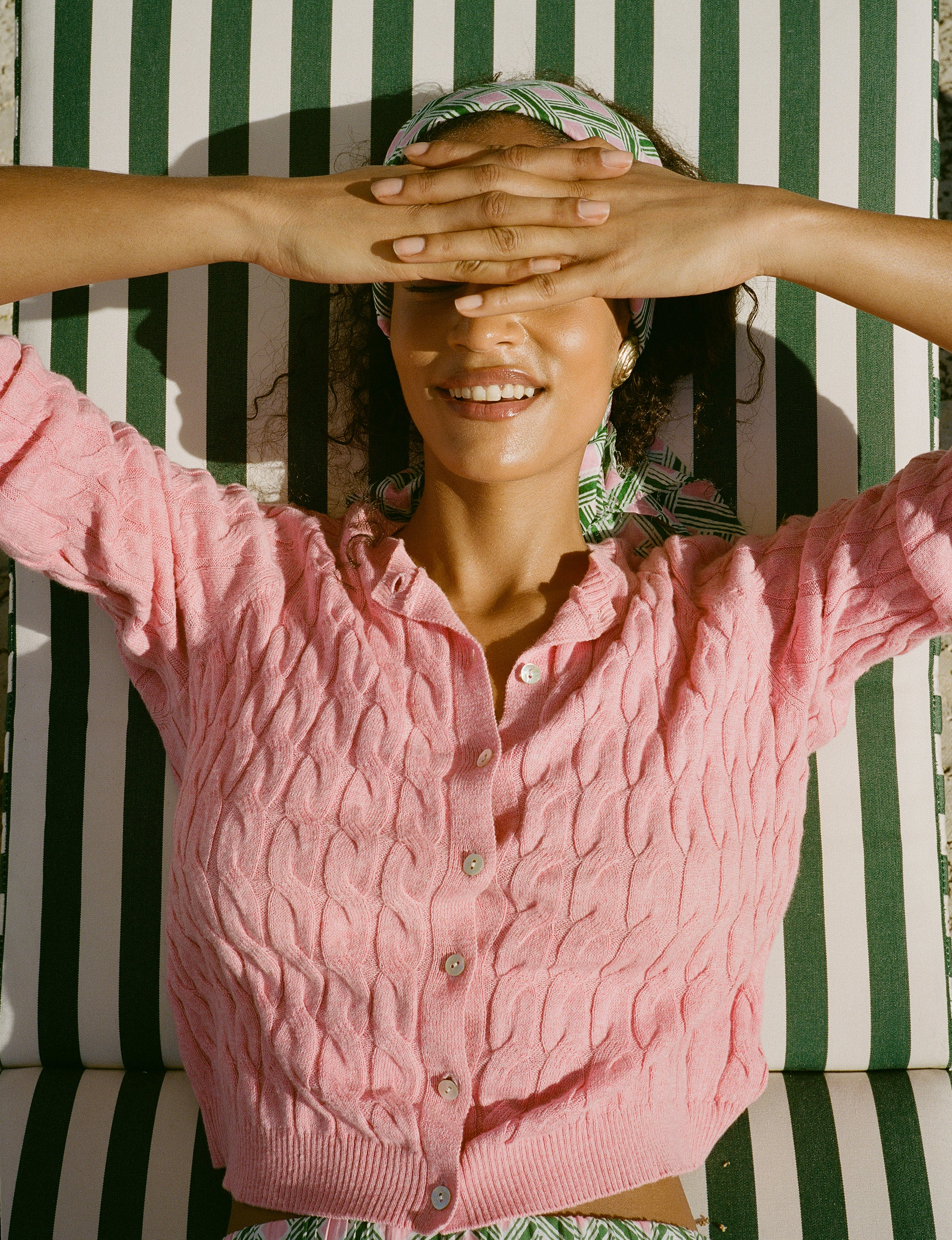 Woman wearing a pink cardigan with a striped background